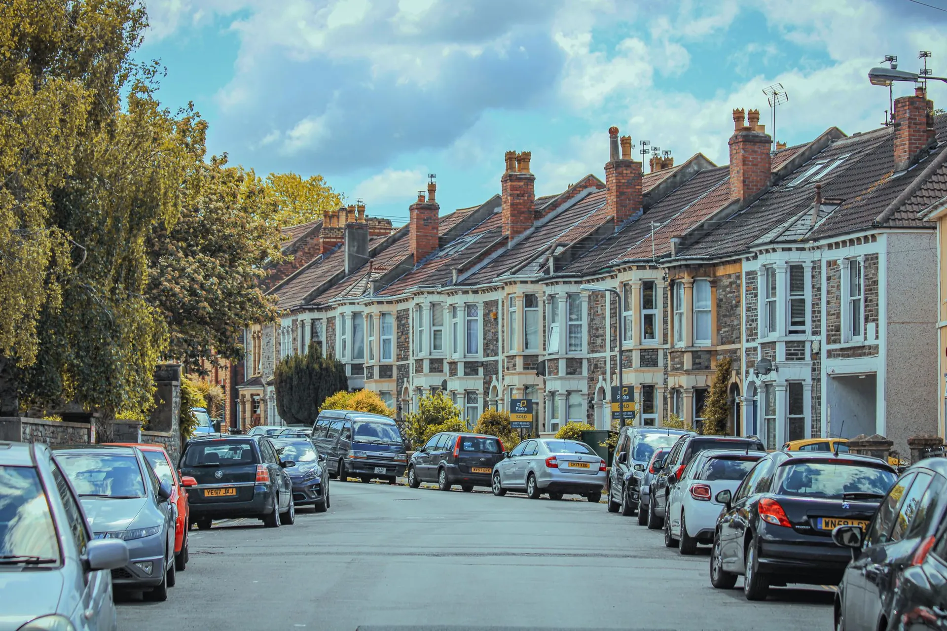 A residential street of houses with cars parked along it